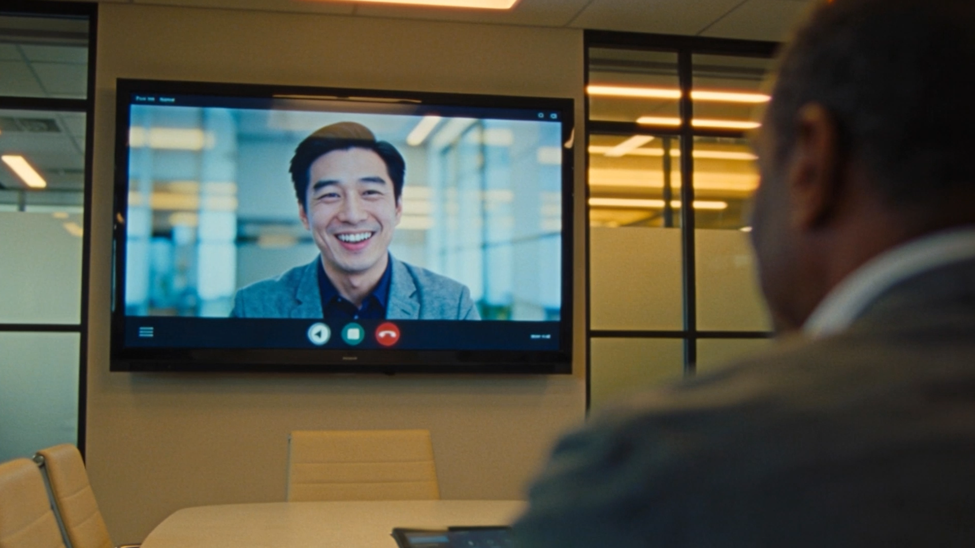 Hybrid meeting in a modern conference room with one person and one remote person on large display
